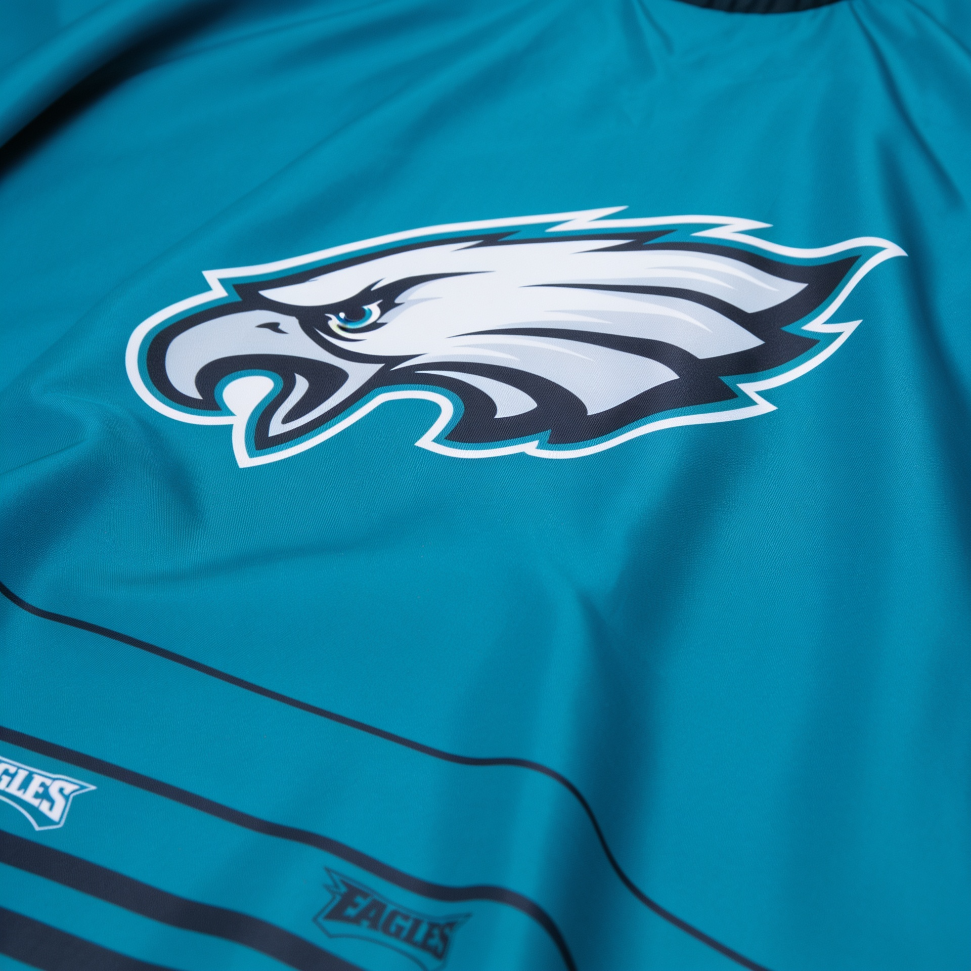 Teal barber cape with an eagle logo on a white background.